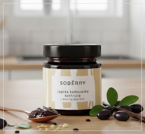 Szklany słoik konfitury z jagody kamczackiej z wanilią bourbon Soberry na dębowym blacie, obok miedziana łyżeczka z konfiturą, laski wanilii bourbon oraz świeże owoce haskap.